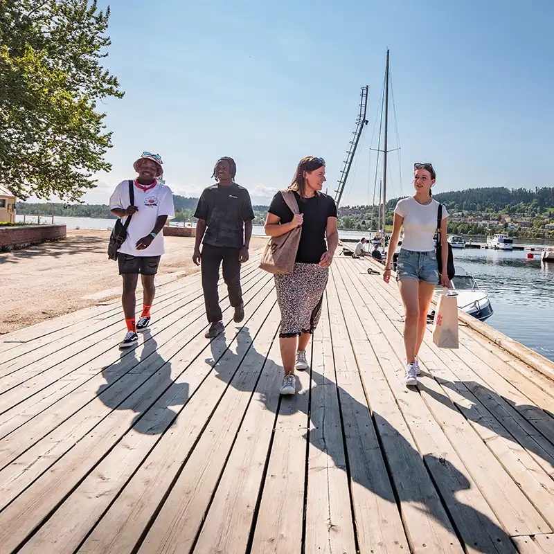Fyra människor promenerar i hamnen sommartid. Östersundspulsen.